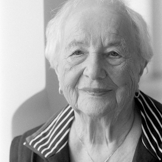 Eine Hand, die sich einem See und der sich dahinter befindenden aufgehenden Sonne entgegenstreckt, Bild in schwarz-weiß