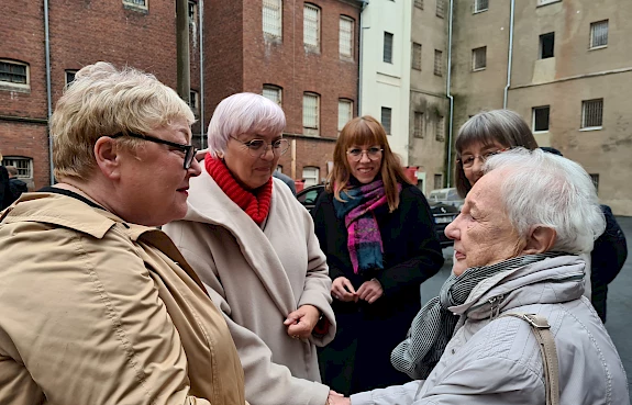 Claudia Roth mit vier weiteren Besucher:innen des ehemaligen Frauengefängnisses Hoheneck vor dem Gebäude.